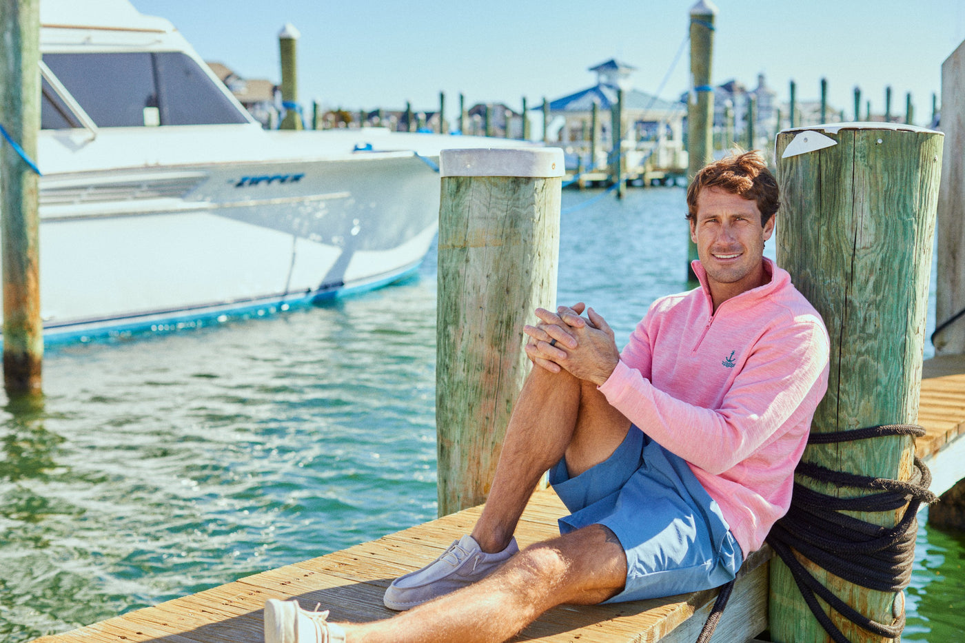 Preppy man on dock with fleece and shorts.